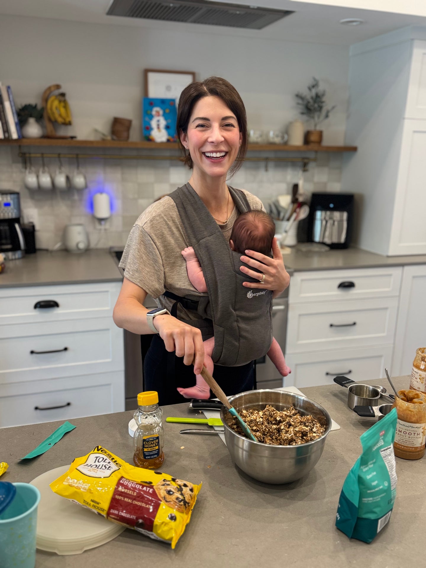 Emily mixing Mama Bites while babywearing her newborn